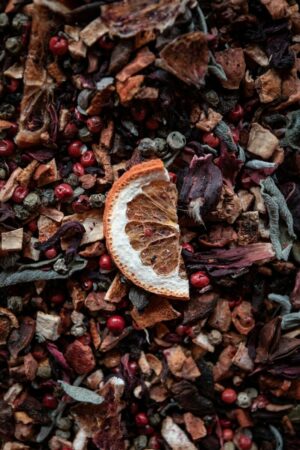 Photo by Pang Yuhao a close up of an orange slice on a pile of dried cranberries